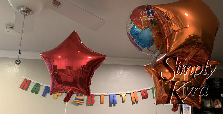 Image shows the balloons floating in front of the LEGO-themed banner on the wall. 