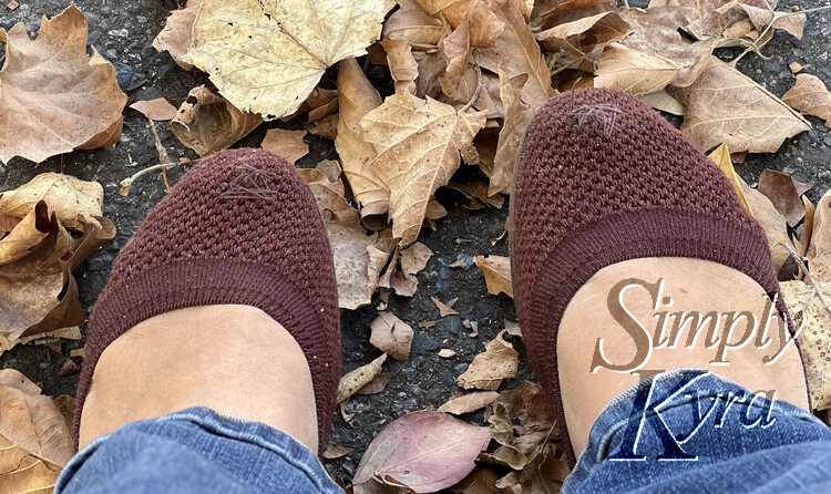 Image is taken looking down at my patched brown shoes while I wear them with jeans. Under my shoes is cement and tons of fallen yellow and tan leaves. 