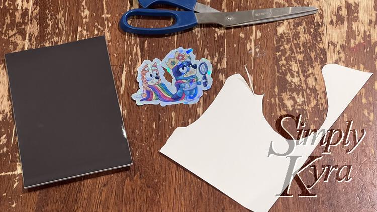 Image shows a new 4x6 inch magnetic sheet, a new shiny sticker, a white remnant of cardstock, and a pair of scissors.