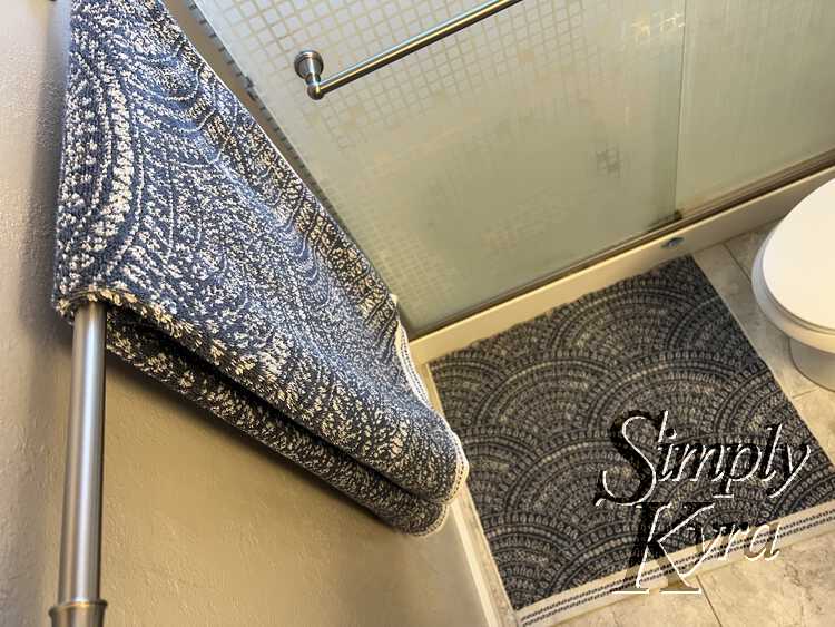 Image is taken from above looking down at a bath towel folded and hung up with the bath mat blurred underneath.