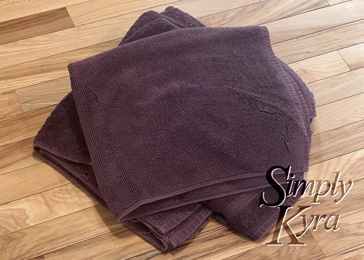Image shows a pile of towels with the bath mat on top. 
