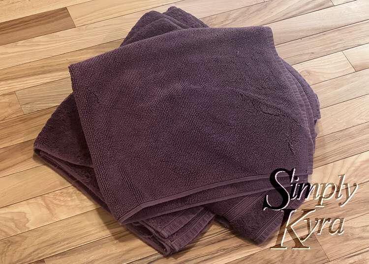 Image shows a pile of towels with the bath mat on top.