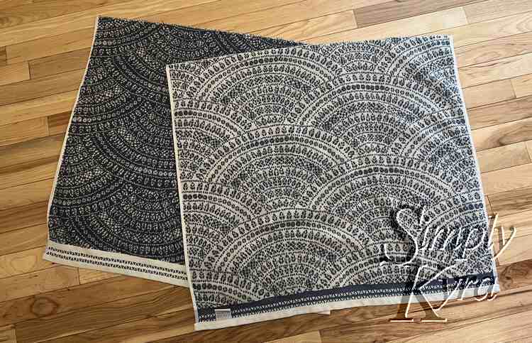 Image shows the same two bath mats as before but now the overlapping one is flipped over to show the underside. Where it was blue it's now white and vis versa making this one more white than blue. 