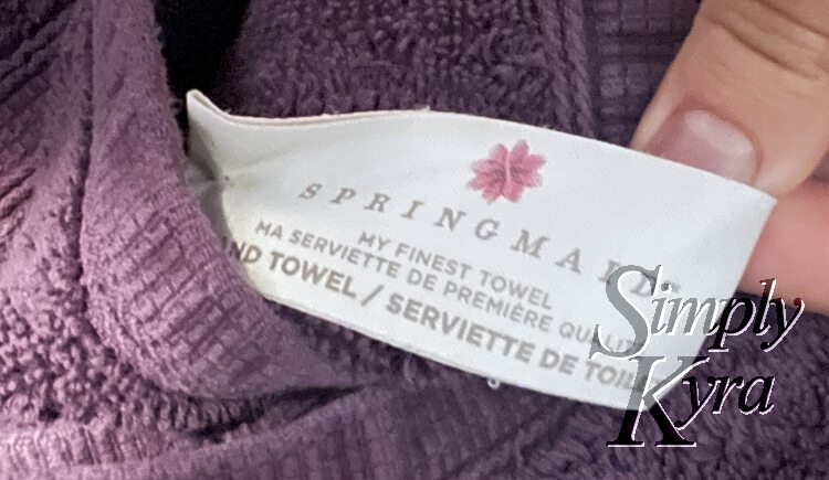 Image shows a closeup of the tag attached to the purple towel. The label says: Springmaid my finest towel. 