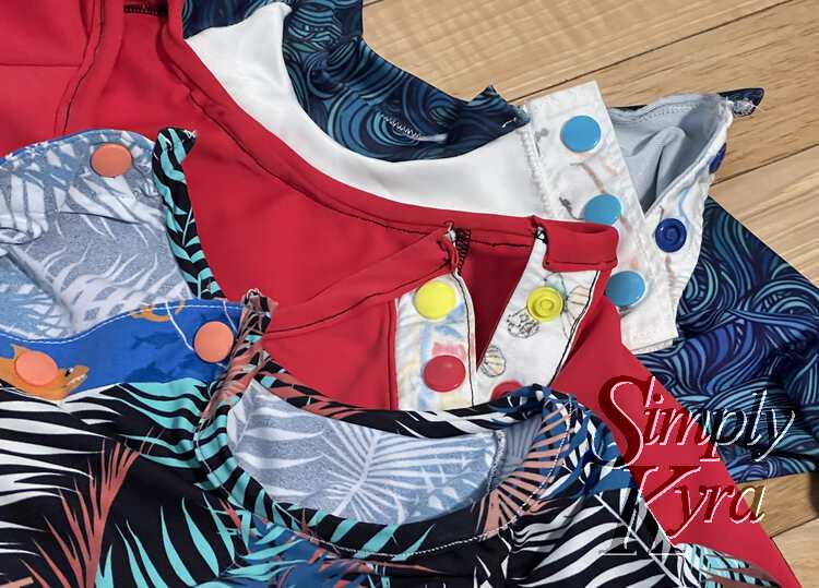 Image shows a closeup of the neckbands and plackets of three of the swimming tops. 