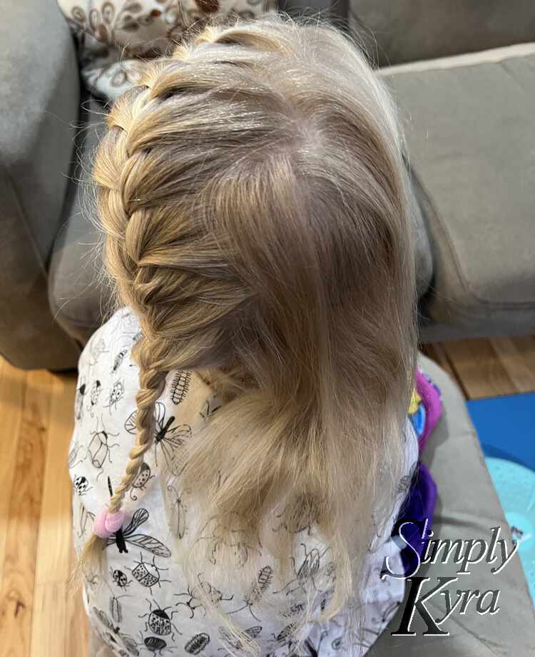 Image shows the back of Zoey's head as she looks up. The braid is finished, the zigzag part visible on the top, and the hair is all brushed back. 