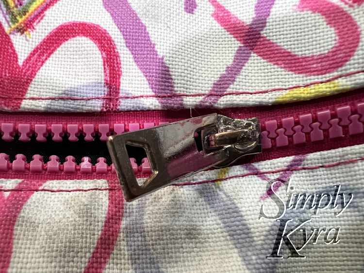 Image shows a closeup of the zipper pull and its clear glue gunned opening. 