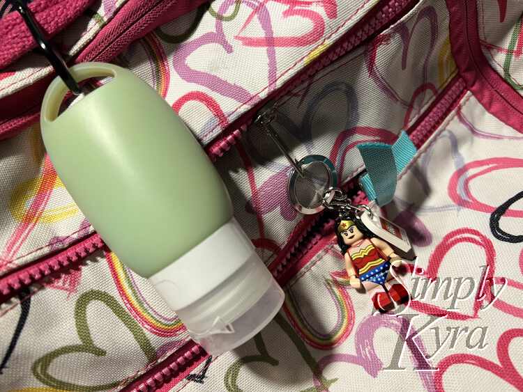 Images shows a green silicone tube attached to Ada's backpack with a Wonder Woman LEGO® keychain attached nearby.