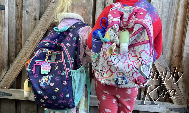 The back of the girls with their ready-to-go backpacks. Water bottles, sunscreen bottles, and decorations completely ready!
