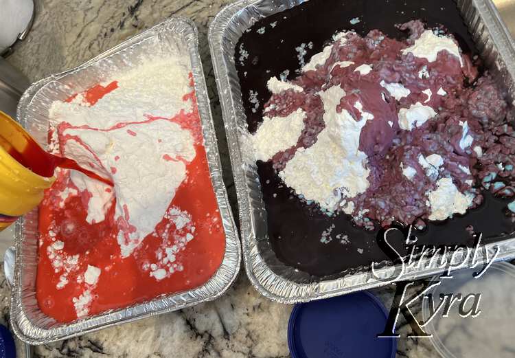 Image shows red water getting poured onto a pile of white cornstarch on the left. The right container is covered in purple water with the odd bit of red and blue making an appearance. 