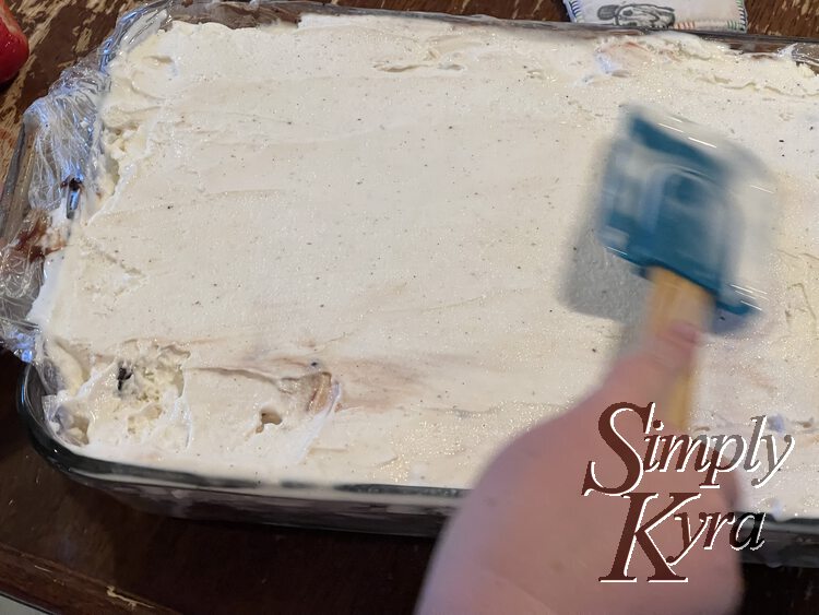 Image shows a moving blurred spatula and a smoothed vanilla ice cream to the top of the casserole dish. 