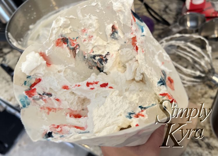 Image shows the inside of the piping bag filled with red and blue dabbed whip cream. In the back some mixed to make a dark purple. 