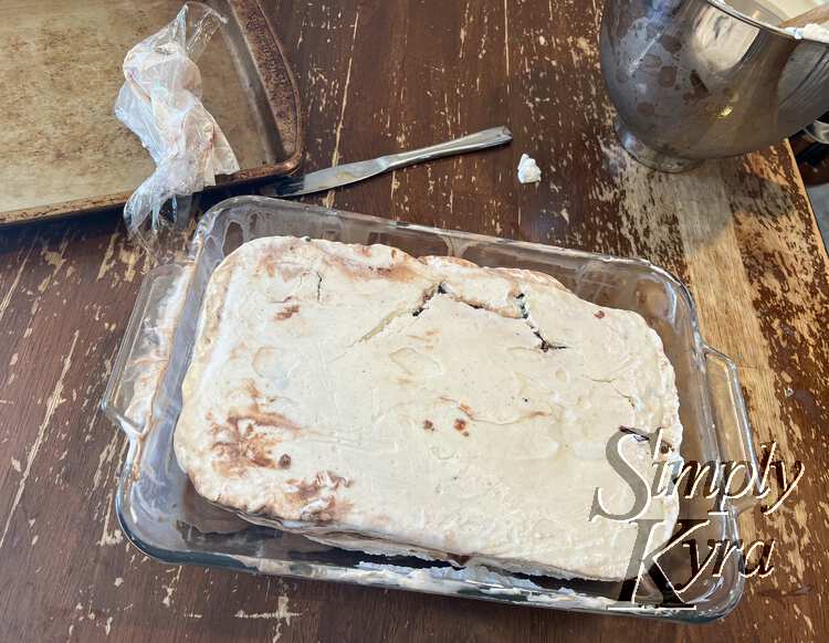 Image shows the glass casserole dish with a cracked white-ish cake with space around the edges. 