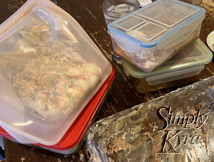 On the left are two containers the kids used for their leftovers while the containers and Stasher bags on the left are fuller with the rest of the cake. The corner of the emptied and dirtied casserole pan sits at the bottom of the image.