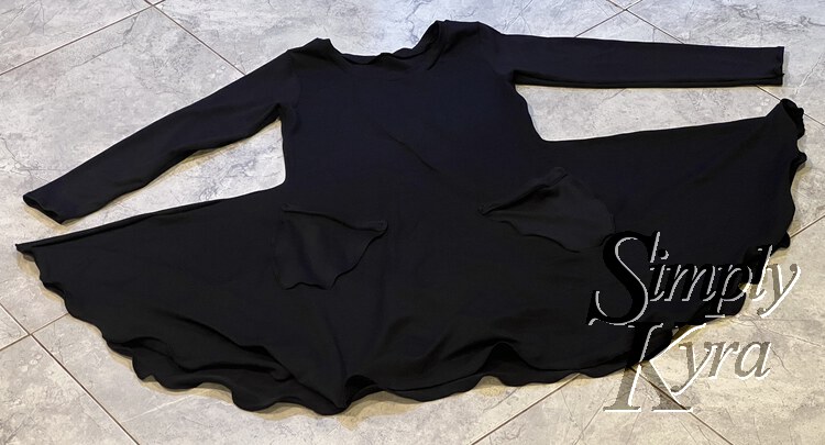 Image shows a flat lay of the black dress on the tiled kitchen floor. 