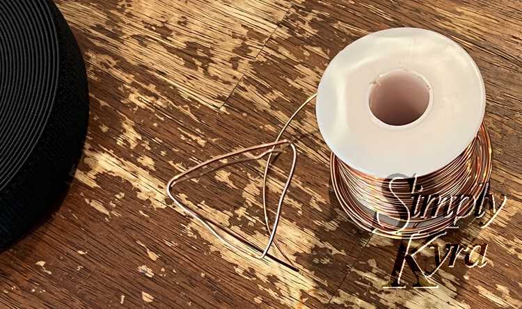 Image shows a loose triangle coming off of a spool of copper wire. 