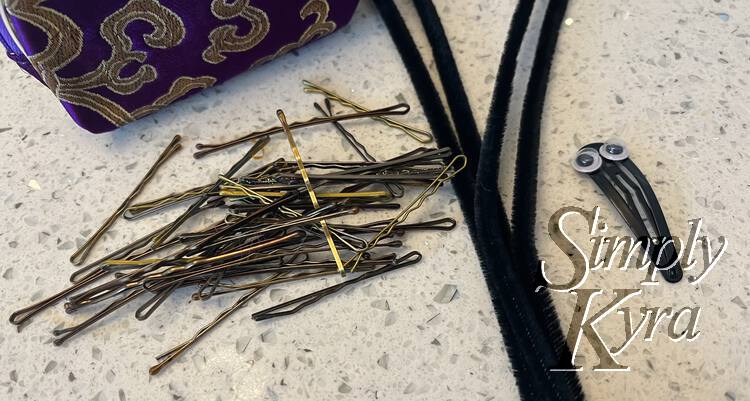 Image shows a pile of bobby pins, four long pipe cleaners, and the googly eyed hair clip. 