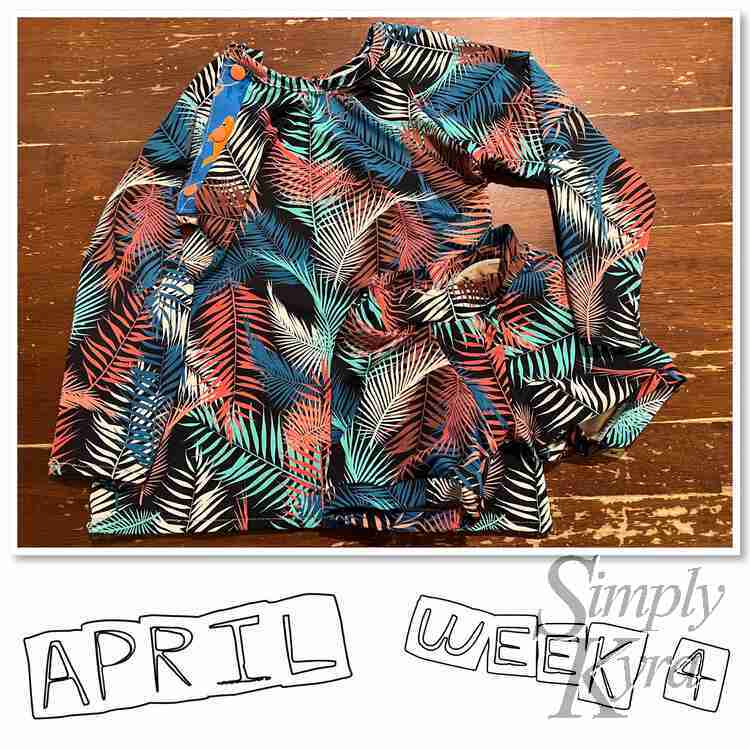 Image shows a flat lay of Zoey's palm frond print swim suit consisting of a long sleeved raglan and matching shorts. There's sharks where the Kamsnaps were placed on the placket. Below it says "April Week 4".