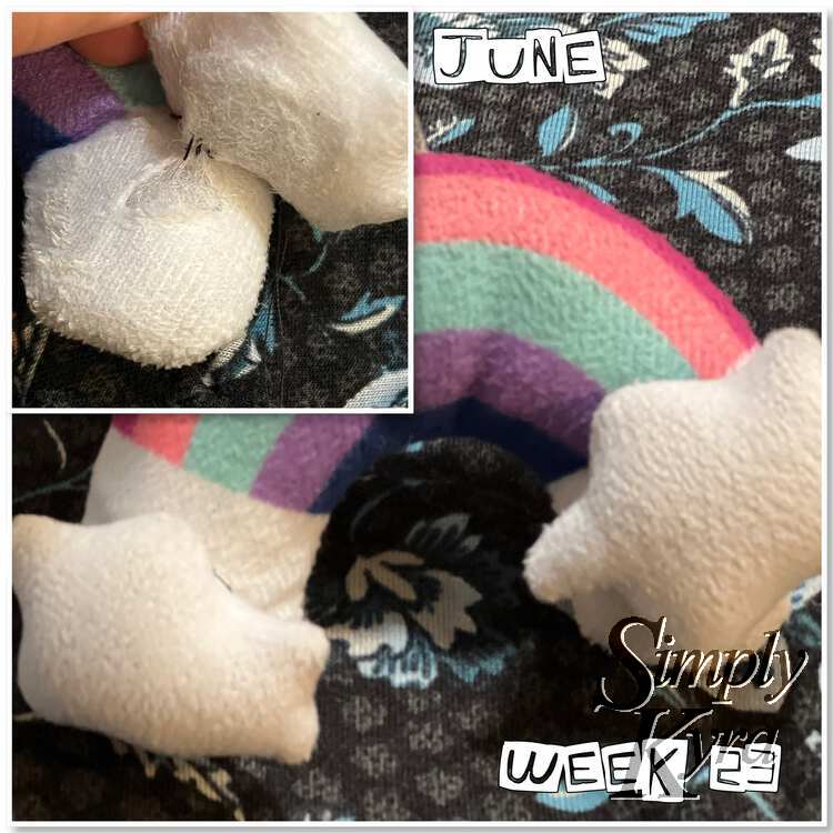 Image consists of two images. The top one is superimposed over the main one and displays the cloud only slightly sewn on showing the hole. The main image shows the finished and fixed rainbow. At the upper right it says "June" while it displays "Week 23" on the lower right.