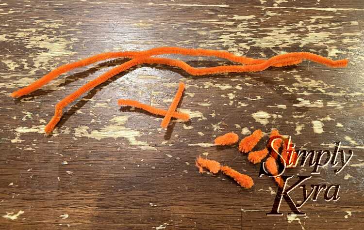 Image shows three piles of pipe cleaners. On the far left arching over the piles are two long and whole pieces. Next, below and to the right, sit two small straight pieces. The bottom right pile shows several finished carrots. 