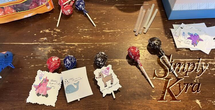 Image shows five lollipops laid out. The three on the left have a card attached while the two on the right only have the glue as they're waiting for the card. 