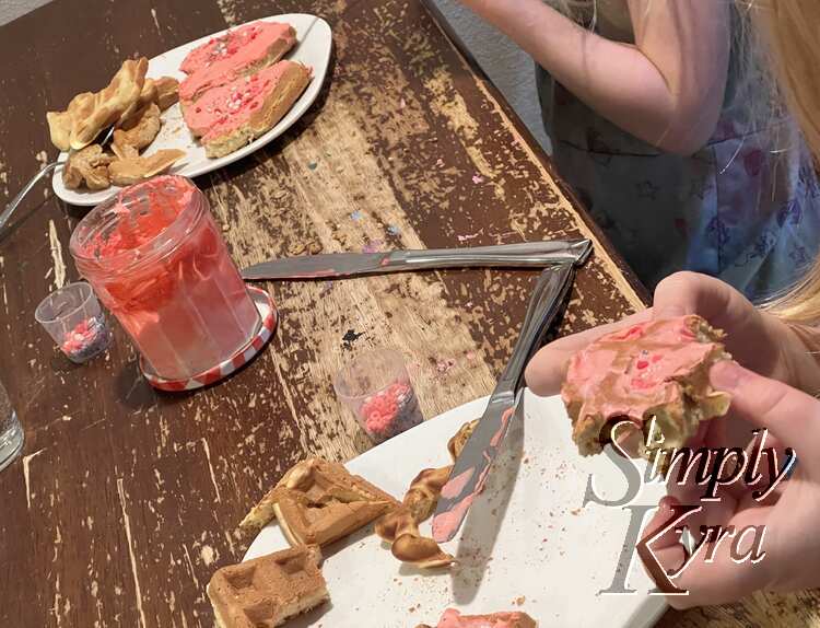 Image shows both plates with the one in front just with edge pieces and Ada about to eat the last of it. In the back the mostly un-eaten hearts sit on Zoey's plate.